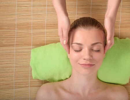 Beautiful young woman getting relaxing head  massage in the spa salon. Top view high resolution shot. Smiling model with closed eyesの写真素材
