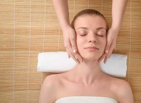 Beautiful young woman getting relaxing head  massage in the spa salon. Top view high resolution shot. Model with closed eyesの写真素材