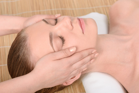 Beautiful young woman getting relaxing head  massage in the spa salon. Top view high resolution shot. Model with closed eyesの写真素材