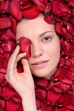 Beautiful woman lying in petal of roses. Top viewの写真素材