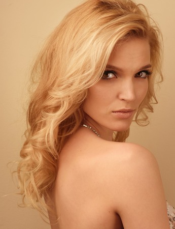 Blonde luxury woman posing. Head shot on peach color backgroundの写真素材