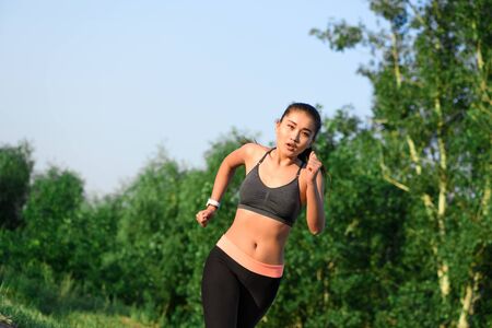 Fit young asian woman jogging at park.の写真素材