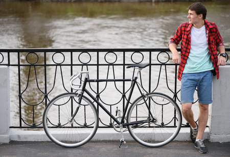 Hipster with bicycle resting over quay. Man looking at the sideの写真素材