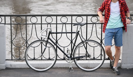 Hipster with bicycle resting over quay. Shot with no headの写真素材