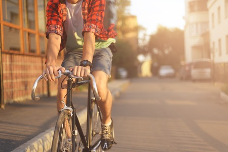 Close up hipster on bike in the city at sunset. Shot with sunflare and without face.の写真素材