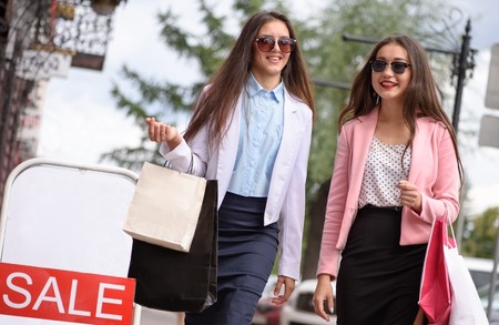 Two asian girl walking with shopping bags. Sale bannerの写真素材