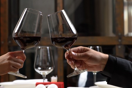 Couple drinking red wine in restaurant. Close-up hands with glasses.の写真素材