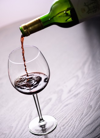 Red wine pouring into glass, close-up shot.の写真素材