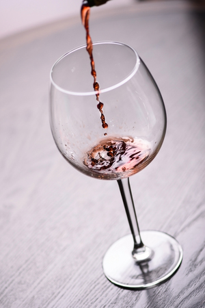 Red wine pouring into glass, close-up shot.の写真素材