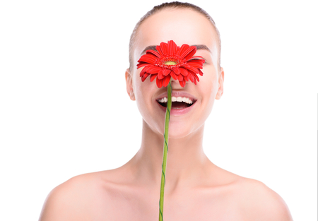 Cheerful beautiful woman hiding over red gerbera. Isolated on white background.の写真素材