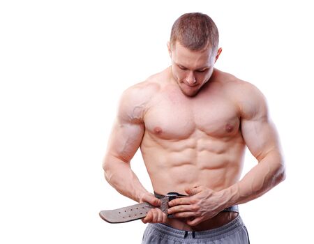 Muscular man fasten lifting belt over white isolated background.の写真素材