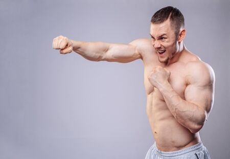 Male boxer making training punches on grey background. Model looking at the sideの写真素材
