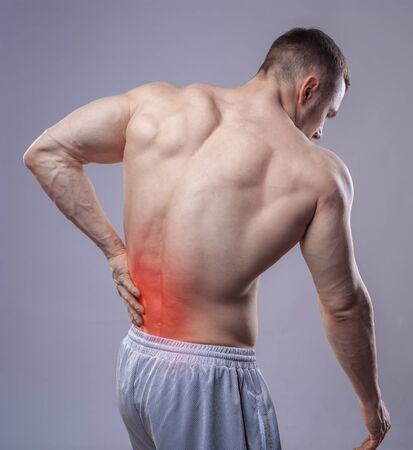 Athlete muscular man has pain in the back. Red spot of backache.の写真素材