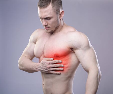 Athletic muscular man has pain in the heart. Red spot of injury.の写真素材