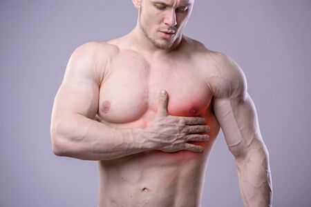 Athletic muscular man has pain in the heart. Red spot of injury.の写真素材