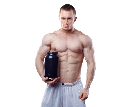 Bodybuilder holding a black plastic jar with whey protein isolated on white background.の写真素材