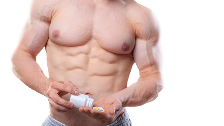 Bodybuilder with jar and pills on isolated white background in studio. Shot without faceの写真素材