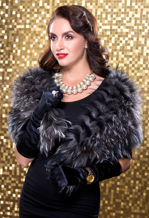 Portrait of elegant brunette retro woman wearing silver fox fur over gold mosaic background. Model looking at the side.の写真素材