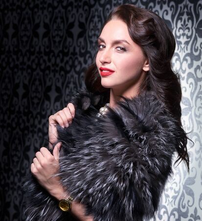Portrait of elegant brunette retro woman wearing silver fox fur over vintage background.の写真素材