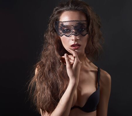 Sensual woman posing over dark background with lace mask on eyes.の写真素材
