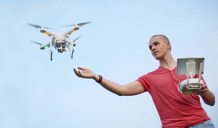 Young man controls a quadrocopter over sky background