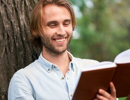 Smiling student in park of campus read a book.の写真素材