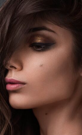 Close-up beauty shot of young pretty model with gold make-up. Eyeliner. Golden makeup and natural lipstickの写真素材