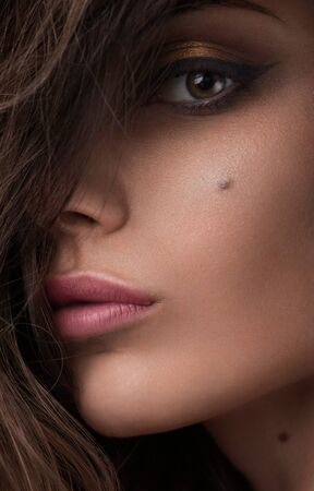 Close-up beauty shot of young pretty model with gold make-up. Eyeliner. Golden makeup and natural lipstickの写真素材