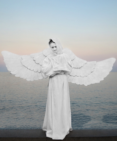 Angel - symbol of love, purity and protection  A girl in a white dress with wings on background of the sea のeditorial素材