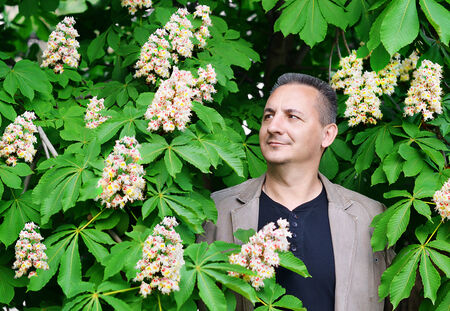 A man stands near a tree - flowering chestnutの写真素材