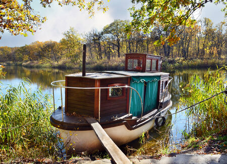 Autumn, water, landscape. Small ship, standing on the quay of the river, in a beautiful locationのeditorial素材