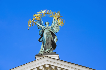 Bronze sculpture of \"Glory,\" with a gold palm branch, on the roof of the Opera and Ballet Theatre in Lvivの写真素材