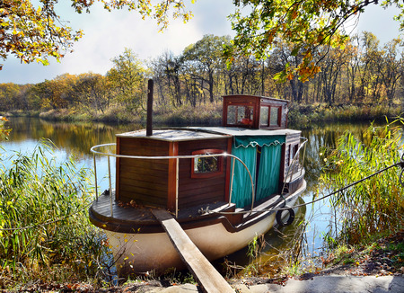 Autumn, water, landscape. Small ship, standing on the quay of the river, in a beautiful locationの写真素材