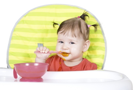 Little baby girl eating a vegetable puree in a highchairの写真素材