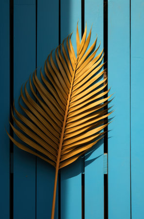 a palm leaf is on a wall close to a fenced in yard with a blue gate.の素材