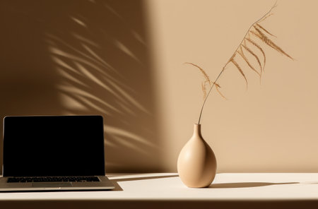 an empty vase and a laptop on top of a table.の素材