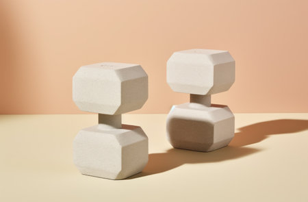 a pair of gray exercise dumbbells are placed on top of a beige table,の素材