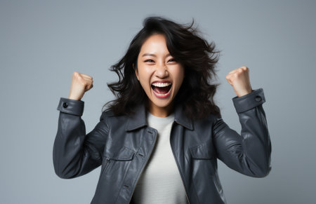 an Asian woman is holding her fist and laughing on white backgroundの素材