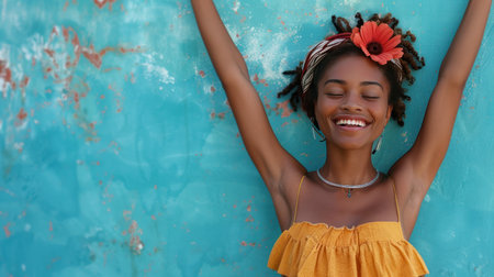 A joyful young woman enjoys dancing in front of a blue wall.の素材