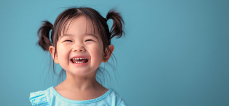 A young girl with a joyful expression wearing a blue shirt and smiling.の素材
