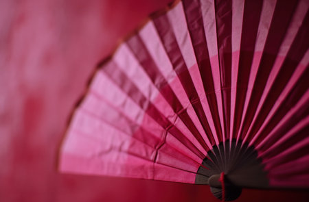 a pink origami fan hangs on a red background.の素材