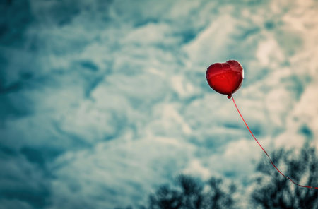 a red heart balloon in the air with a red line across it.の素材