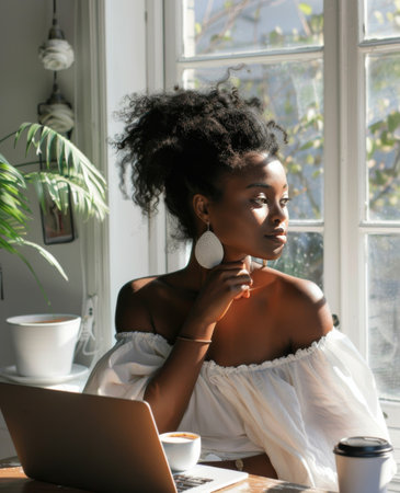 A woman is sitting in front of a laptop computer, working or studying intently.の素材
