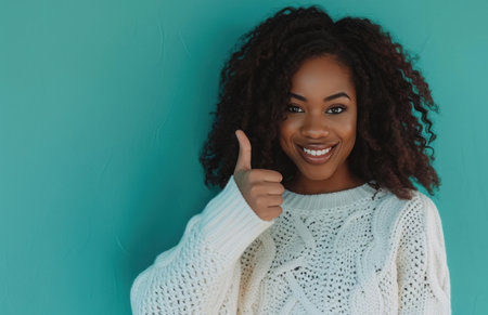 ctp afroamerican young woman in white sweater with thumbs up while pointing to right.の素材