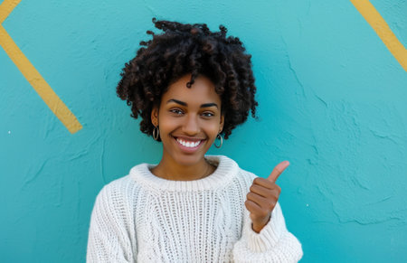 ctp afroamerican young woman in white sweater with thumbs up while pointing to right.の素材