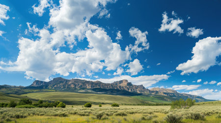 A panoramic view of towering mountains against a brilliant blue sky epitomizes summer beauty.の素材