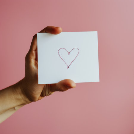 A person is holding a card with a heart drawn on it.の素材