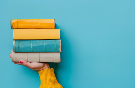 A person standing, holding a stack of books in their hands.の素材