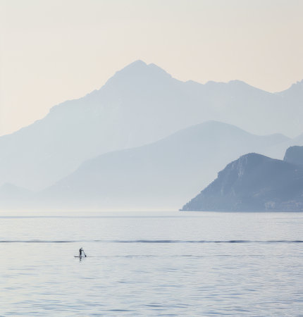 A person is skillfully balancing on a surfboard while standing in the clear water.の素材