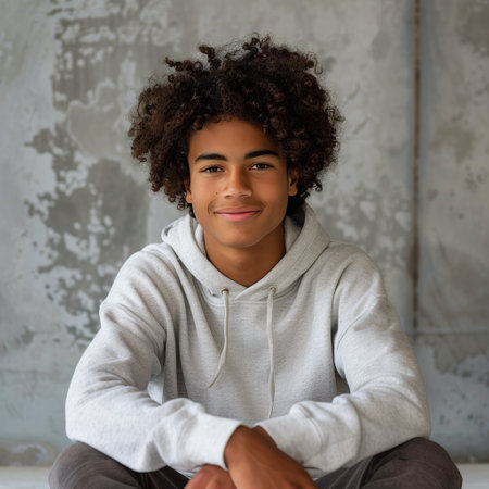 A young man in casual attire sitting on the ground with his legs crossed in a simple and relaxed pose.の素材